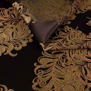Ekskluzywny materiał obiciowy Diva z bogatym, błyszczącym złotym ornamentem na ciemnym tle