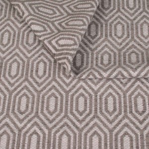 Zbliżenie na strukturę tkaniny tapicerskiej o wzorze geometrycznym. Popielate, kontrastowe linie tworzą wzór wydłużonych sześciokątów (heksagonów) na jasnoszarym, melanżowym tle.