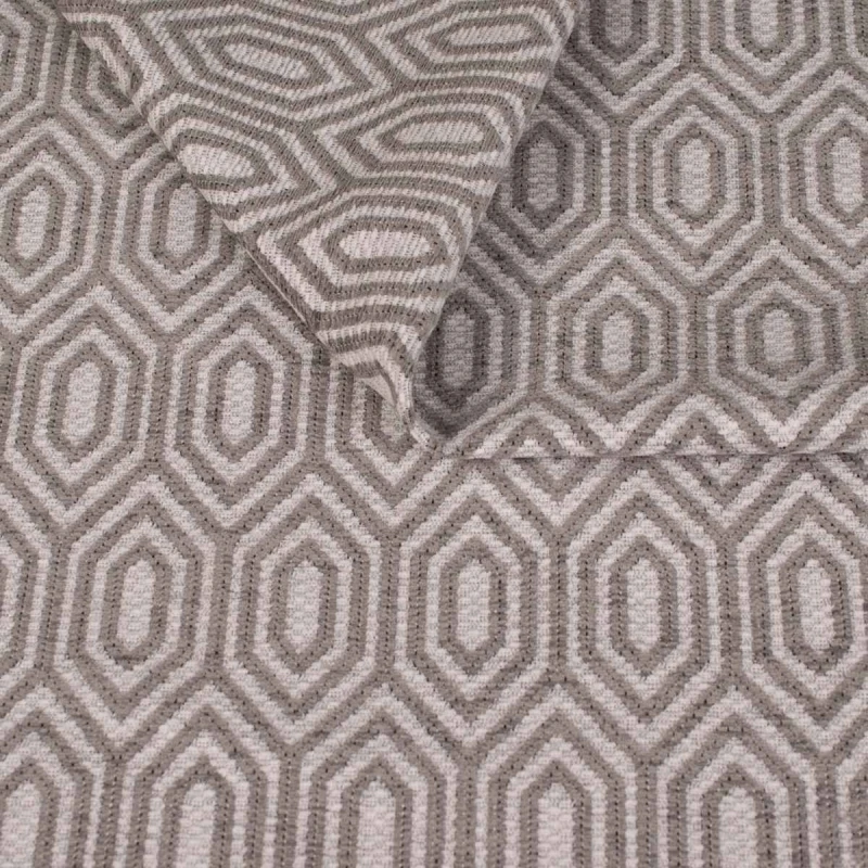Zbliżenie na strukturę tkaniny tapicerskiej o wzorze geometrycznym. Popielate, kontrastowe linie tworzą wzór wydłużonych sześciokątów (heksagonów) na jasnoszarym, melanżowym tle.